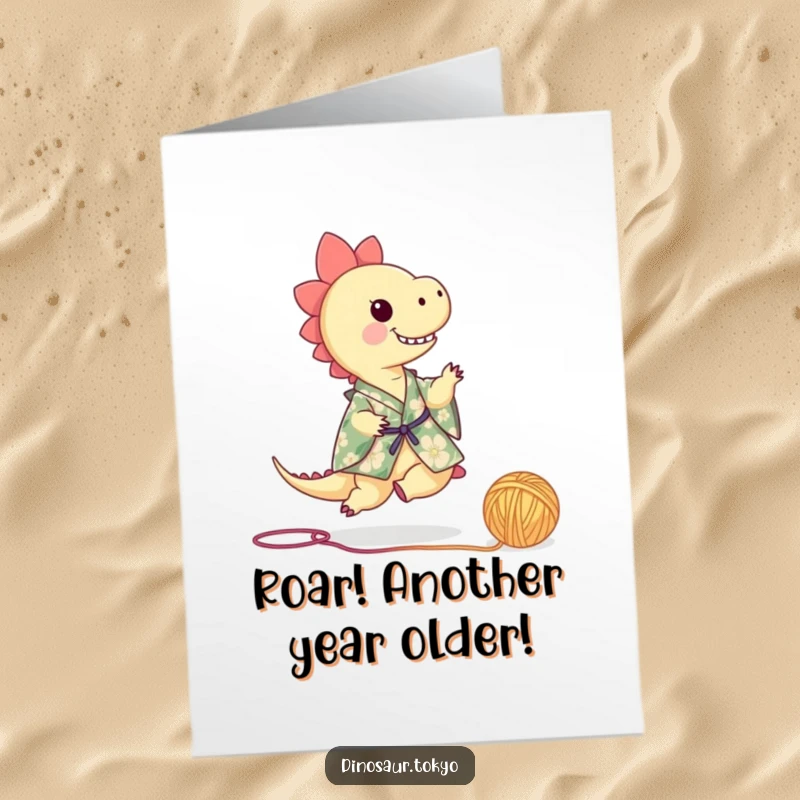 Funny Free Printable Birthday Card: Tiny dinosaur in floral kimono playfully kicking a ball of yarn, ready to party.